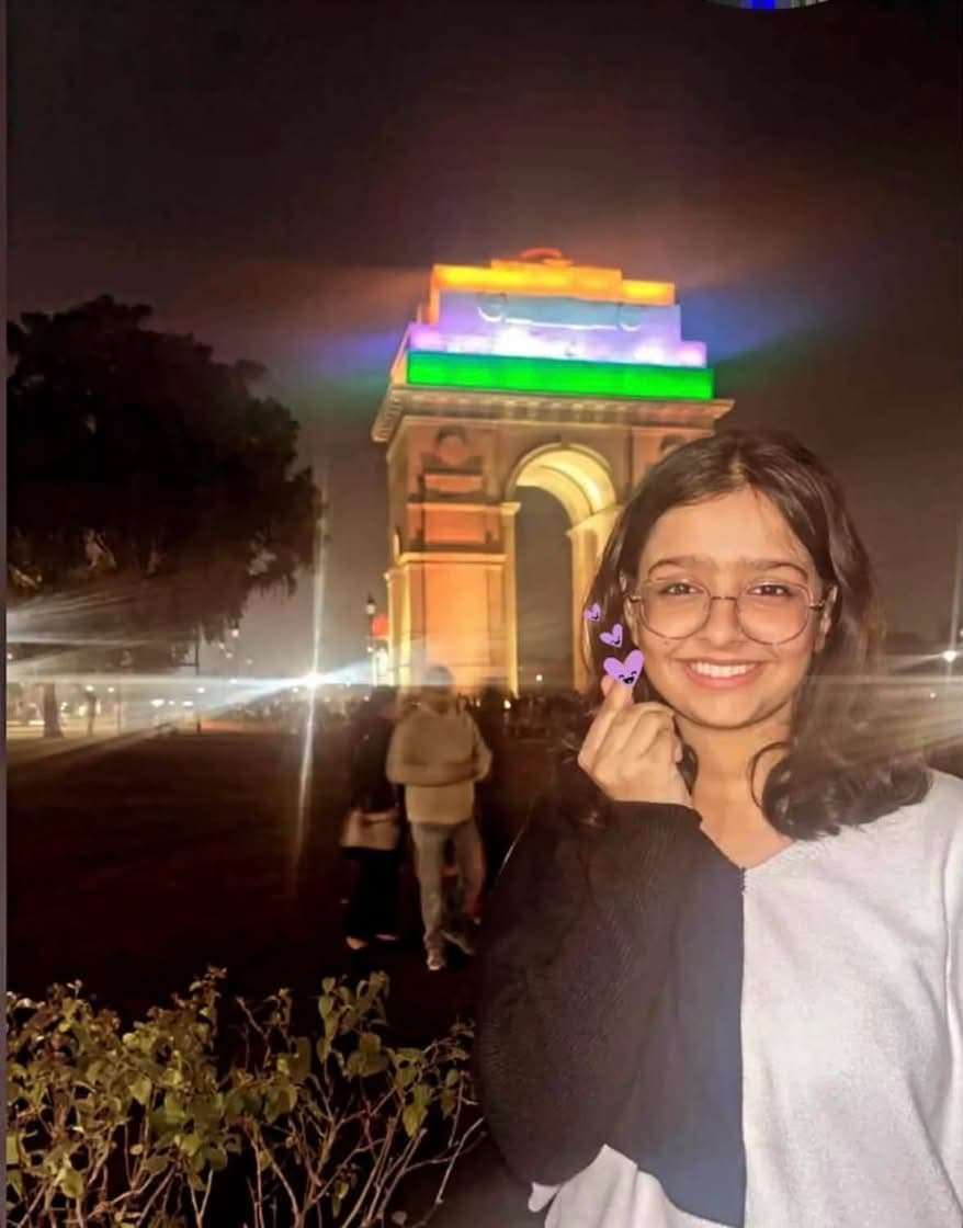Sunidhi Kumari smiling in front of India Gate, New Delhi, lit up in tricolour at night